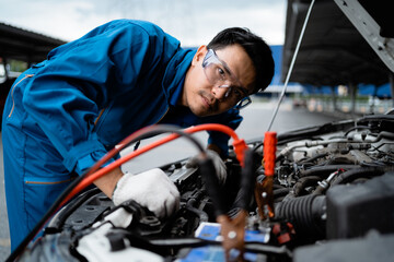 Professional mechanic and check the car battery with jumper wires in the engine compartment. Professional service concept. Repair service concept. Auto mechanic in the service cente