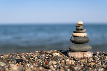Fototapeta na wymiar Pyramid stones on pebble beach, Happy holidays. Concept of happy vacation on the sea, meditation, spa, calmness.