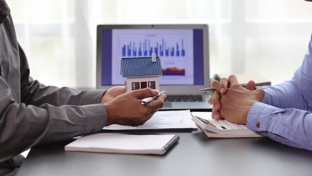Businessmen discuss real estate project ideas and plan budget allocations to maximize profits. Real estate agents who are talking about homes are offering customers the prices of housing projects.