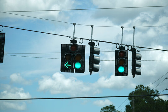 Bright green go traffic lights high above street on blue sky background