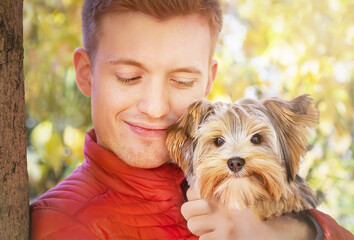 Animals, friendship concept. Handsome man holding yorkshire terrier with cute expression on natural...