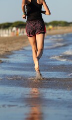 slender athletic young girl running barefoot on the seashore