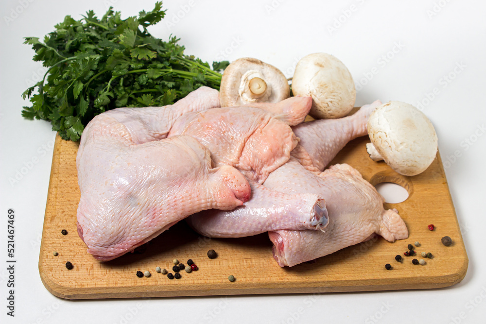 Canvas Prints Chicken legs isolated on white background. Chicken meat with vegetables and herbs on a wooden cutting board.