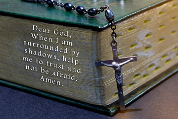 Prayer with the cross over bible on wooden table with window light, vintage tone
