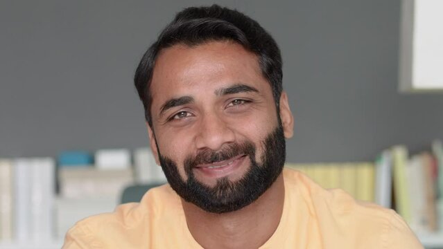 Happy smiling positive handsome wealthy bearded 30s indian ethnic man looking at camera feeling cheerful, relaxed and satisfied at home indoors. Close up front male face portrait.