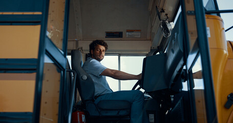 Fototapeta na wymiar Man driver sitting schoolbus cabin alone. Young chauffeur opening vehicle door.