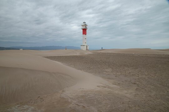 Far del Fangar lighthouse on the beach in Tarragona, Spain, in cloudy sky background