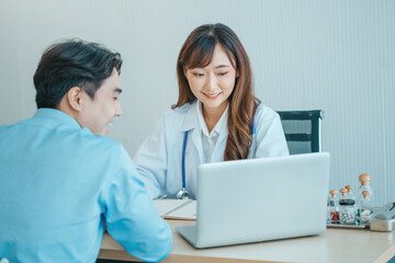 Female doctor and young male patient while consult and .explain. Doctor and patient sitting together at table in examination room.