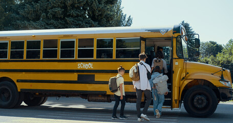 Energetic teen students rushing into school bus. Happy schoolchildren boarding.