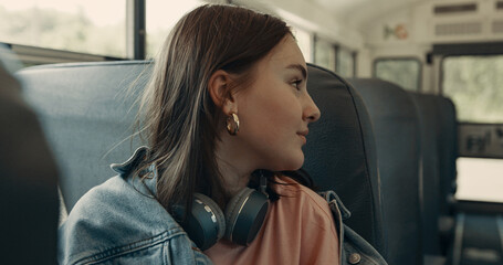 Schoolgirl sitting school bus close up. Teenager girl talking with classmates. 