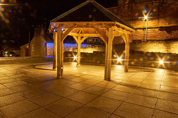 Glenluce New Village Square wooden gazebo at night with light flares. Defocused rain water droplet bokeh