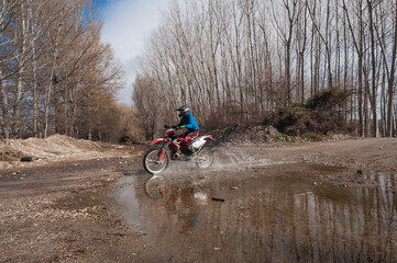 Motorcycle ride along the river with a splash of water.