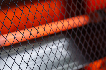 Close-up of grille and heated tube of quartz heater for home use, selective focus.