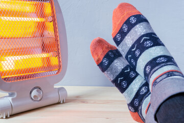 Feet in wool socks are warmed next to the electric heater.