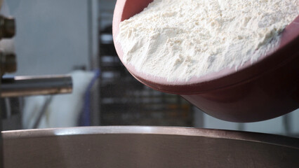 Close up for white flour being put to the iron bowl at the bakery, bread products concept. Stock...