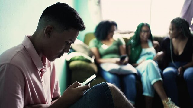 Concentrated hispanic man looking at phone screen. People at home
