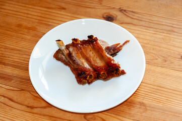Grilled pork ribs on a white plate on the table. Top view. copy space