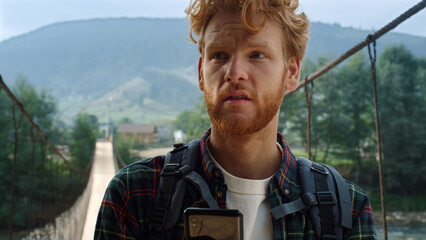 Sad traveler reading mobile phone screen. Hitchhiker looking map in mountains.
