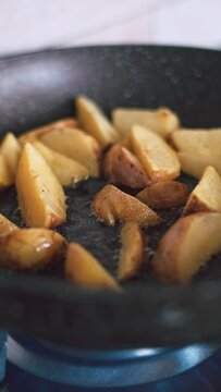 Vertical closeup of potatoes frying in a pan
