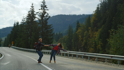 Backpackers dancing mountains road. Cute couple hold hands on nature travel trip