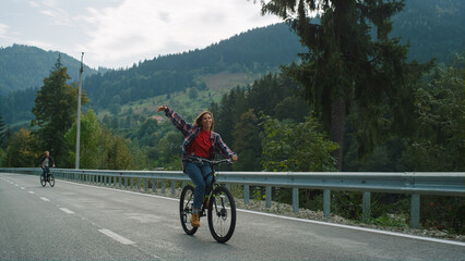 Obraz premium Friends cycling forest road on sport bikes. Carefree travelers enjoy mountains.