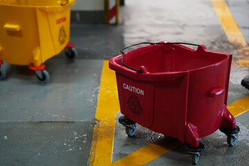 Red and yellow mop bucket and set of cleaning equipment in the office