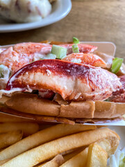 Lobster roll. Close up of lobster roll with French fries. Lobster meat - claw, knuckle, and tail meat, tossed with mayonnaise and celery bits, served on a hot dog roll. Selective focus. 