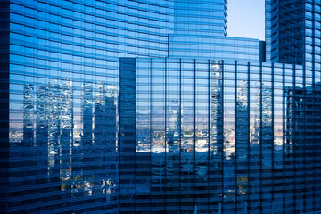 Skyscrapers and blue sky reflected in a glass facade of a modern skyscraper.
