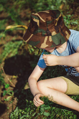 child eating dill on the garden bed