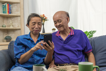 Asian elderly using mobile phone connection online internet communication technology at home.
