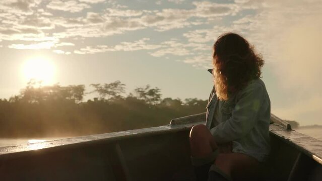 Turista latina mirando el amanecer en bote cruzando el Amazonas 