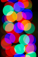 Dancing holiday bokeh lights glowing in deep jewel tones overlap in a colorful rainbow design pattern