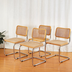 Fototapeta premium Angle View of Set of Chrome & Cane Cantilever Cesca Chairs on wood floor before luxurious white curtains