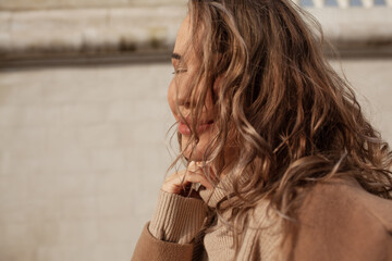 portrait of a style woman walking, enjoys a wonderful atmosphere of a vacation in fall time. The girl is wearing a urban beige sweater,  