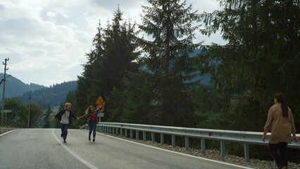 Hikers couple jumping road in mountains forest. Positive lovers enjoy honeymoon.