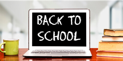 back to school concept on laptop with books and cup of coffee on wooden board near blur background 