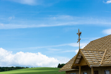 budowa domu, wiecha na dachu, w tle pola i niebieskie niebo