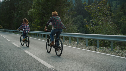 Couple enjoying bicycles trip on mountains highway. Two bikers cycling on road.