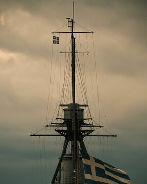 Vertical view of the mast of the historic Greek Averof warship against the gray cloudy sky
