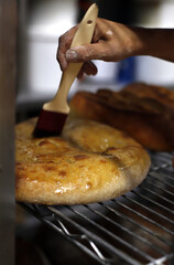 repostero untando huevo batido en un pan artesanal recién horneado, con la ayuda de un pincel