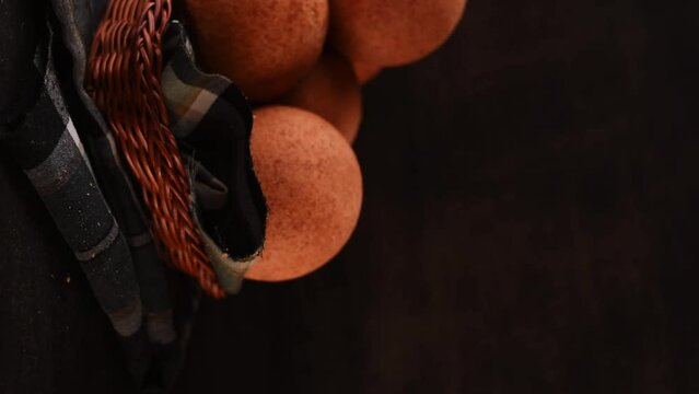 Vertical video of a hand taking a round colombian traditional food named bu&ntilde;uelo in a basket on black wooden table 