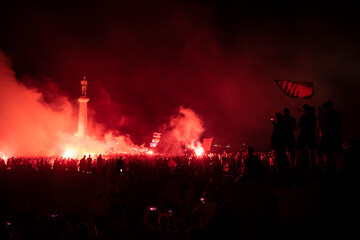 Red Star Football fans with torches and flags celebrating league title win next to monument...
