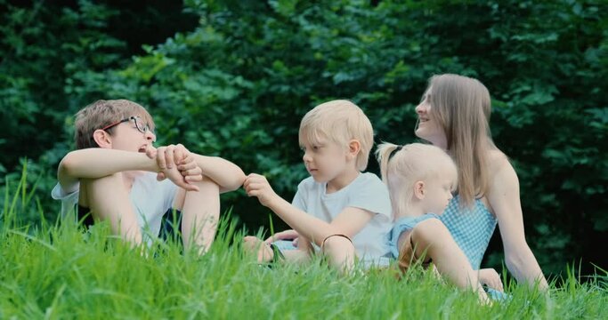 Mother And Three Children Have Fun In The Park On The Lawn With Easy Communication. Joint Pastime. Summer Vacation Or Picnic.