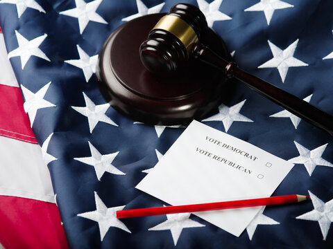 Elections, voting. Vote Democrat, Vote Republican - inscriptions on sheets of paper, a wooden gavel of a judge against the background of the state American flag. Rule of law, patriotism.