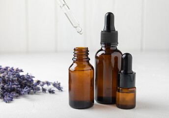 Obraz na płótnie Canvas Essential oil of lavender on a white texture background. Spa concept. RELAX. Bottle with fragrant oil and lavender flowers.Aromatic oil with lavender scent.mockup of lavender essential oil.Copy space.