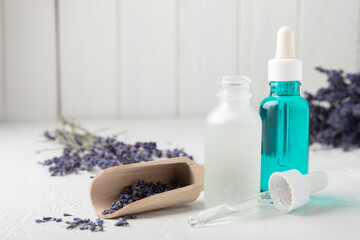 Essential oil of lavender on a white texture background. Spa concept. RELAX. Bottle with fragrant oil and lavender flowers.Aromatic oil with lavender scent.mockup of lavender essential oil.Copy space.