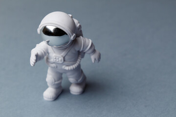 Fototapeta premium Cosmonautics Day. Toy astronaut in motion with outstretched hand. Astronaut on a gray background. Foreground. Top view. Close-up. Place to copy.
