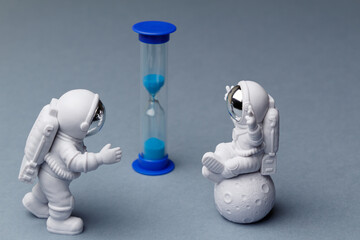 Space day. Greeting toys astronauts standing opposite each other in front of an hourglass on a gray...