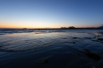 Sandy Beach on the West Coast of Pacific Ocean. Canadian Nature Landscape Background. Sunny Sunset Twilight. Cox Bay, Tofino, Vancouver Island, BC, Canada.