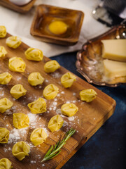 Close-up. Cooking homemade dumplings with meat filling. Appetizing dumplings on a wooden cutting board on a dark background. Home cooking recipes, family traditions.